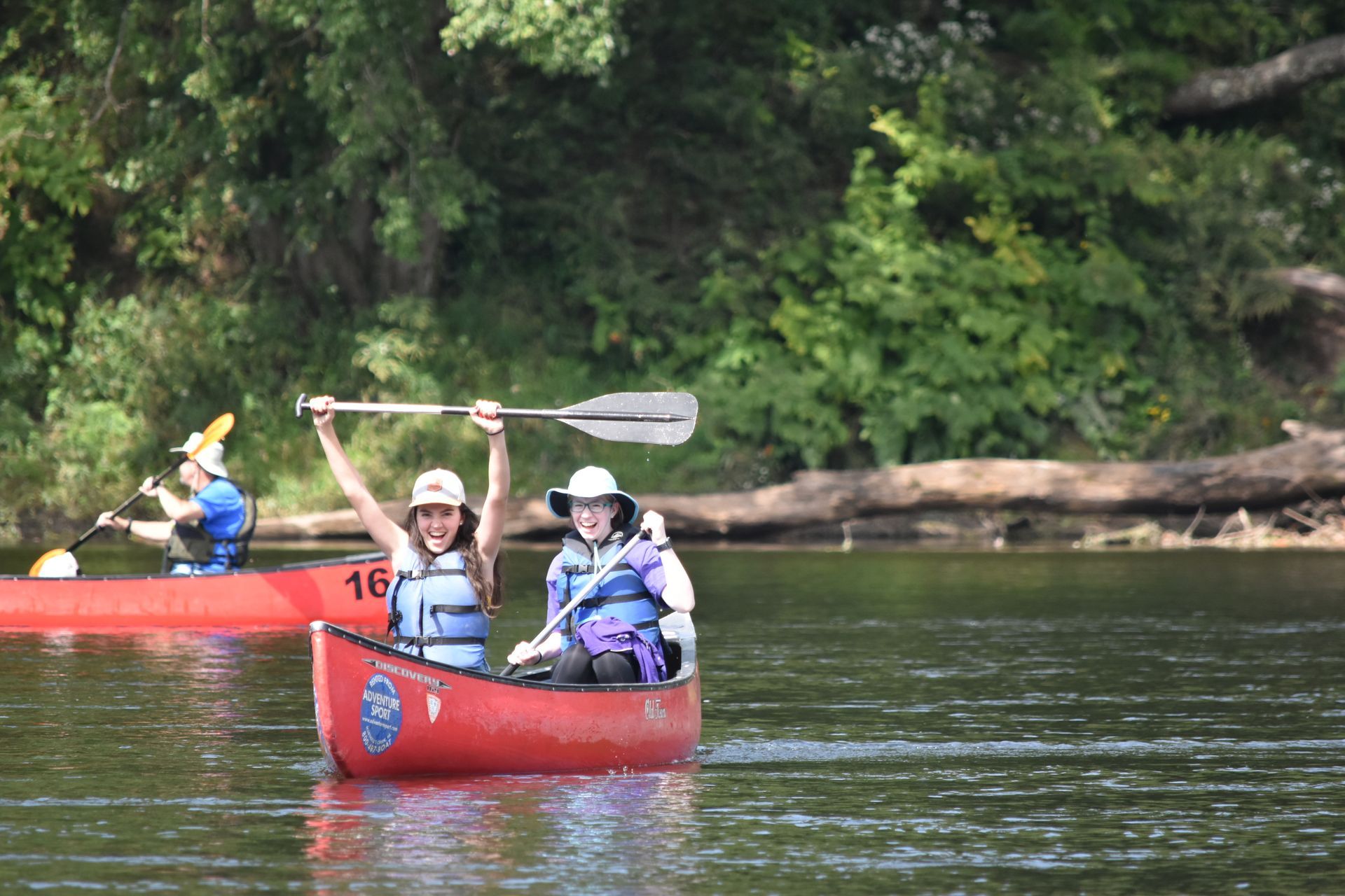 A group of people are rowing an adventure sports canoe on a river.