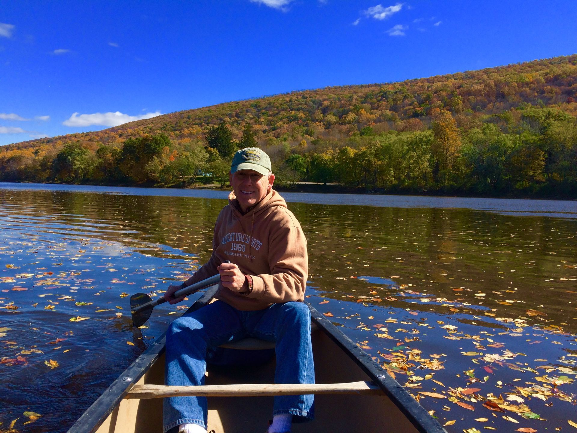 A man is sitting in an adventure sports canoe on a lake holding a paddle.