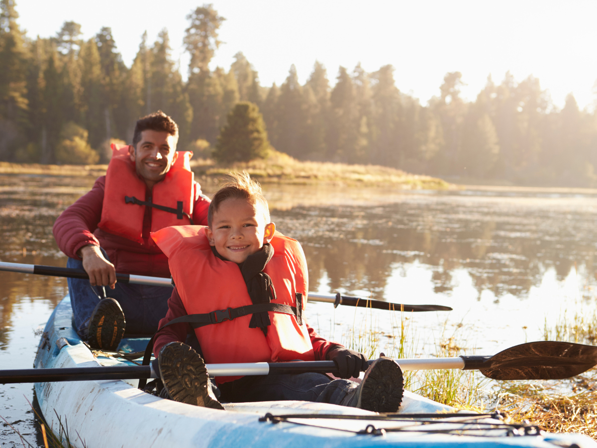 A man and a child are in a kayak on a lake.
