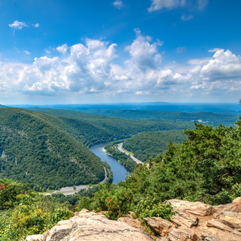 A river flowing through a valley surrounded by trees and rocks in the Poconos near adventure sports