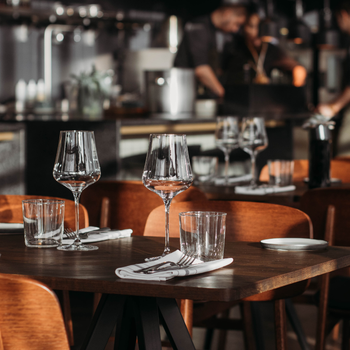 A restaurant with a lot of tables and chairs and wine glasses on them near adventure sports