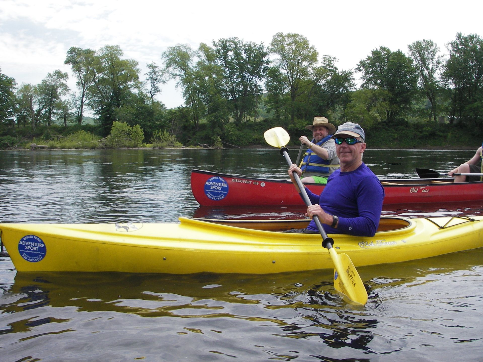 A man in a yellow adventure sports kayak is holding a paddle