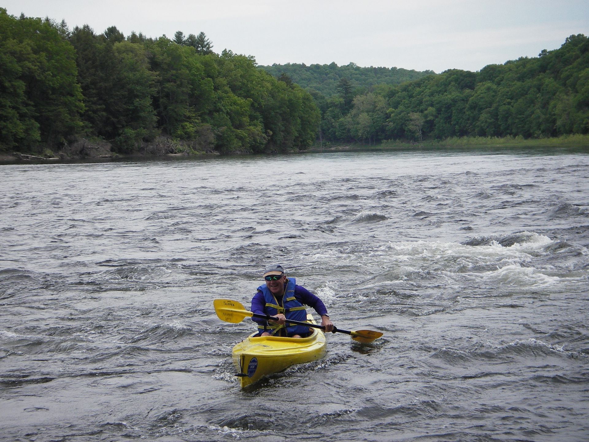 A man is paddling a yellow adventure sports kayak on a river