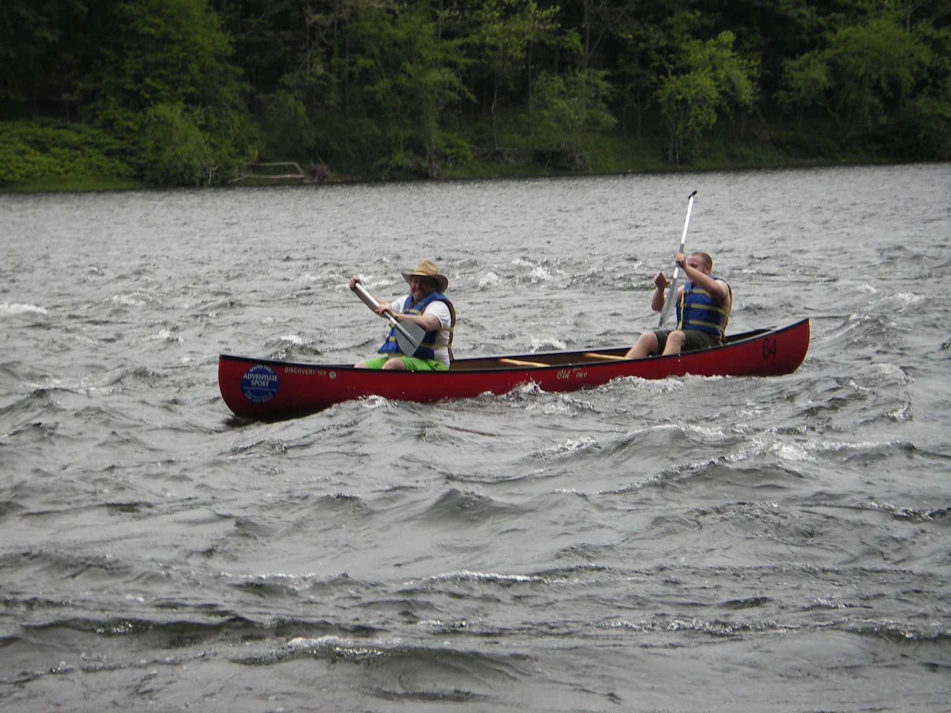 Two people in a red adventure sports canoe on a river