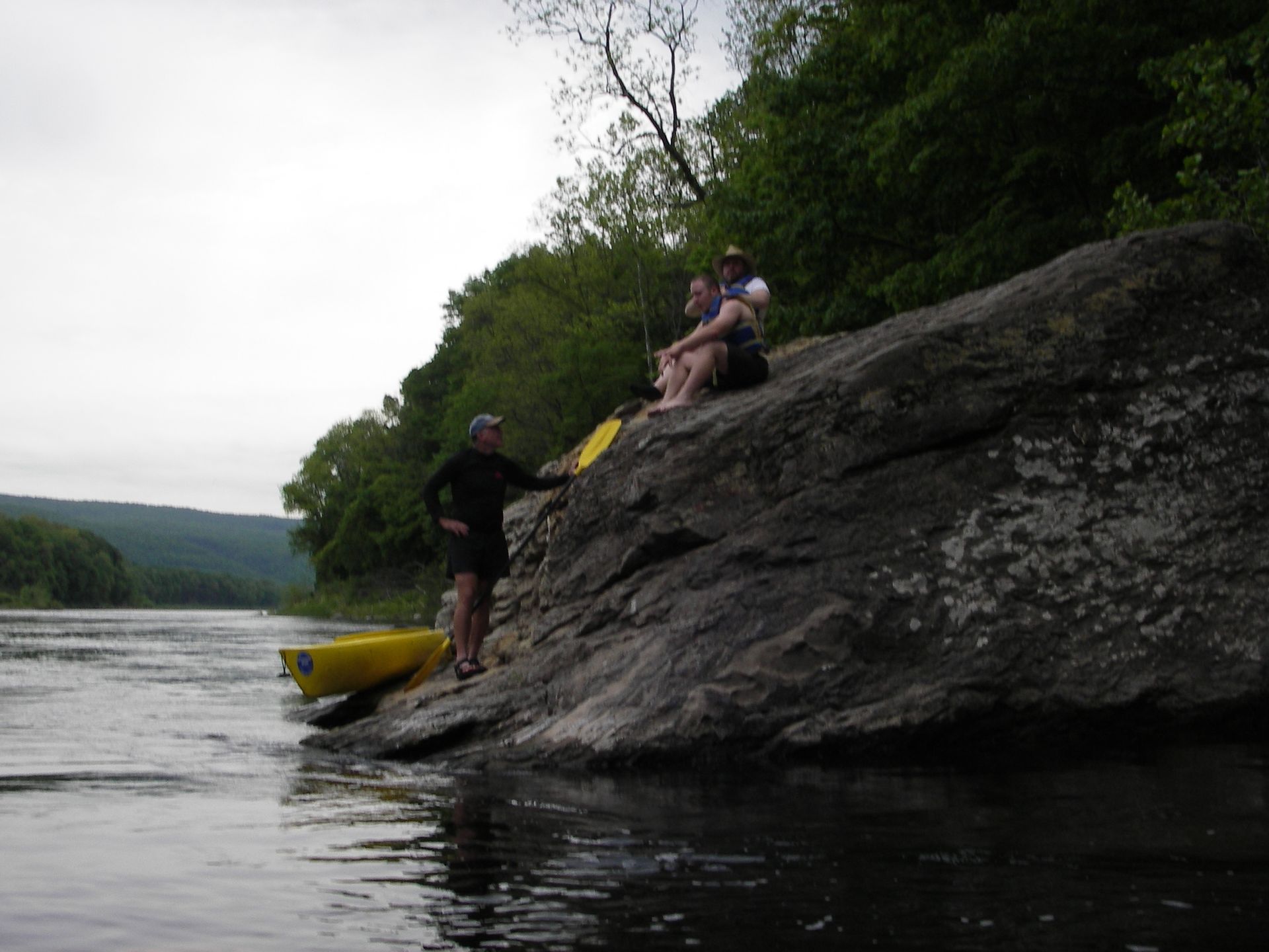 A group of people are sitting on a rock near the Delaware river