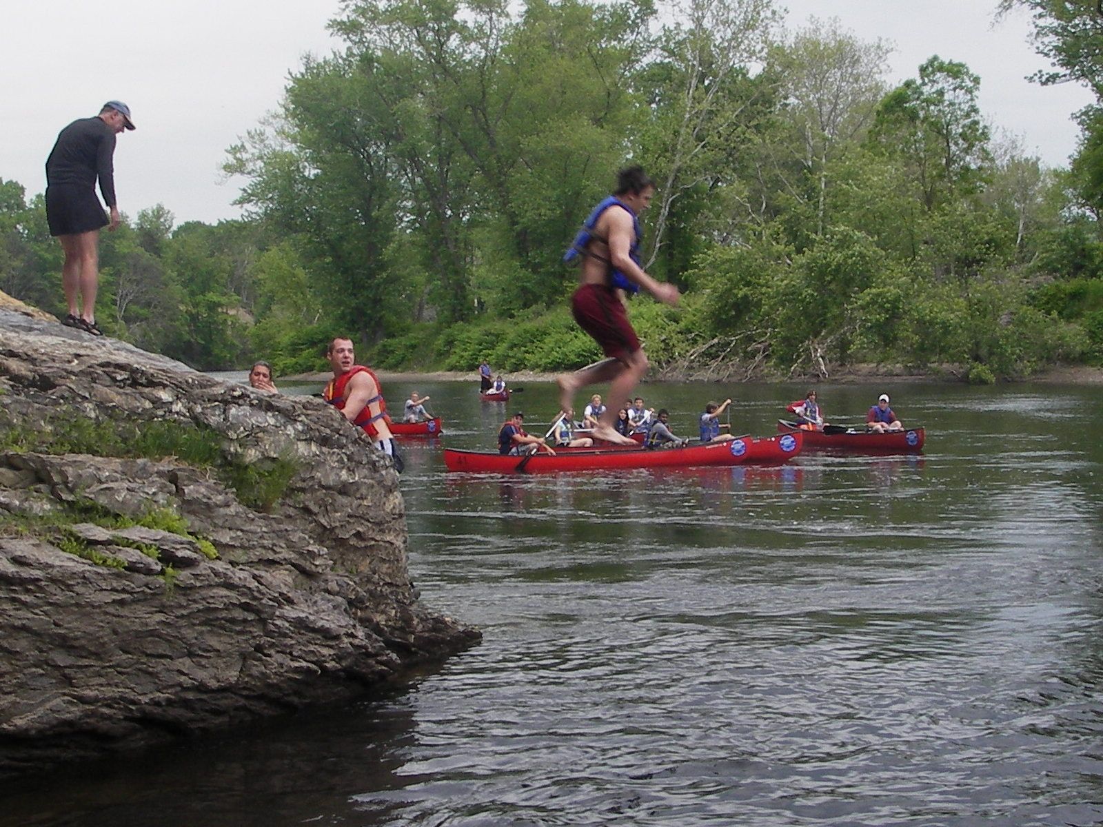 A group of people are jumping into the Delaware river from a rock