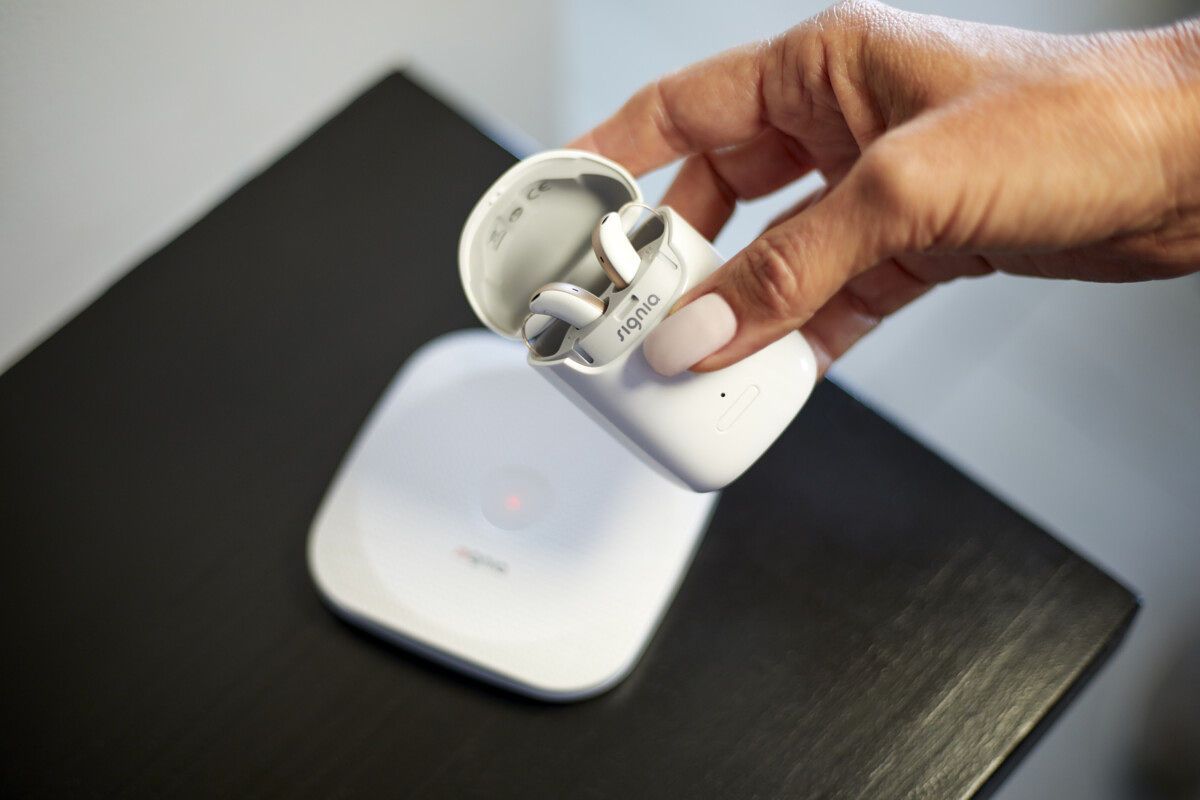 Una persona sostiene un par de auriculares en su mano.