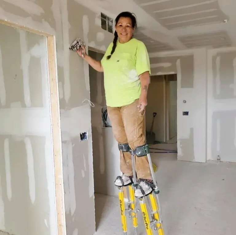 A woman in a yellow shirt is standing on a ladder