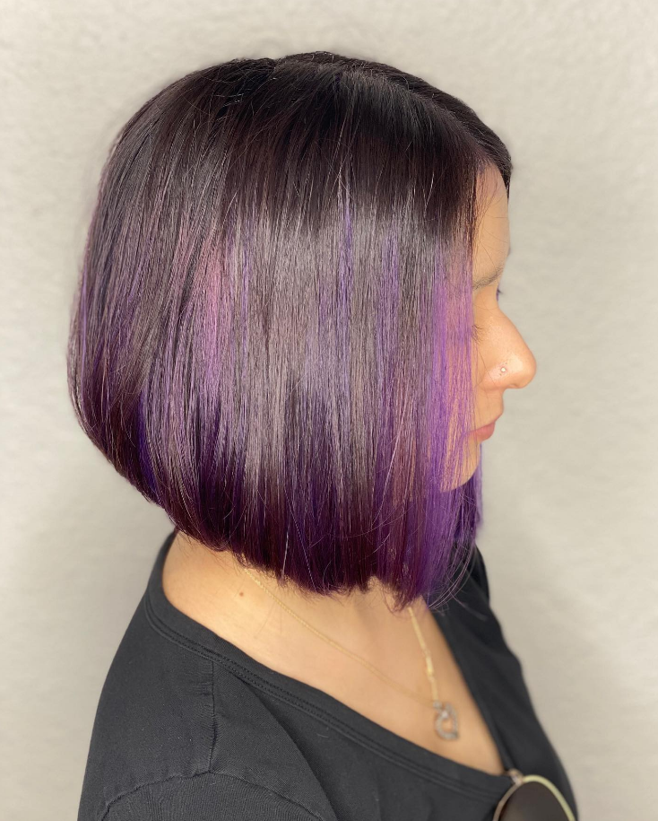 Side-profile haircut with sleek chin-length bob dyed deep purple and black, shown against a neutral background.