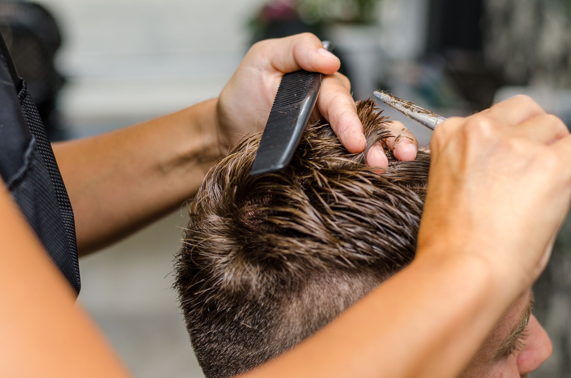 Barber cutting a man’s hair with clippers and comb in a close-up salon scene