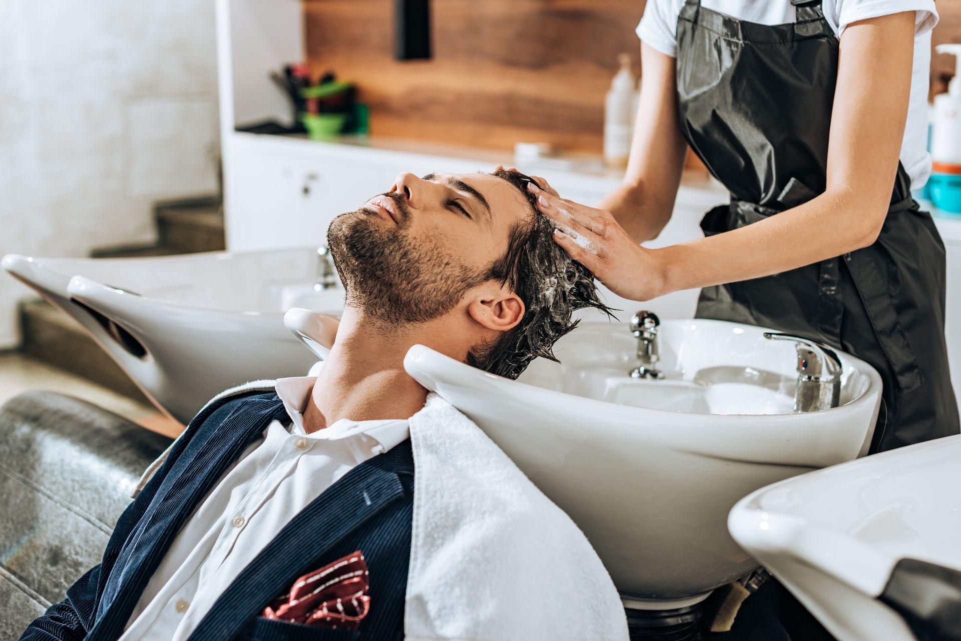 Client getting hair washed at a salon shampoo bowl while reclining in a chair