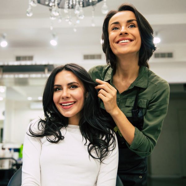 Smiling client getting a dark haircut in a bright salon