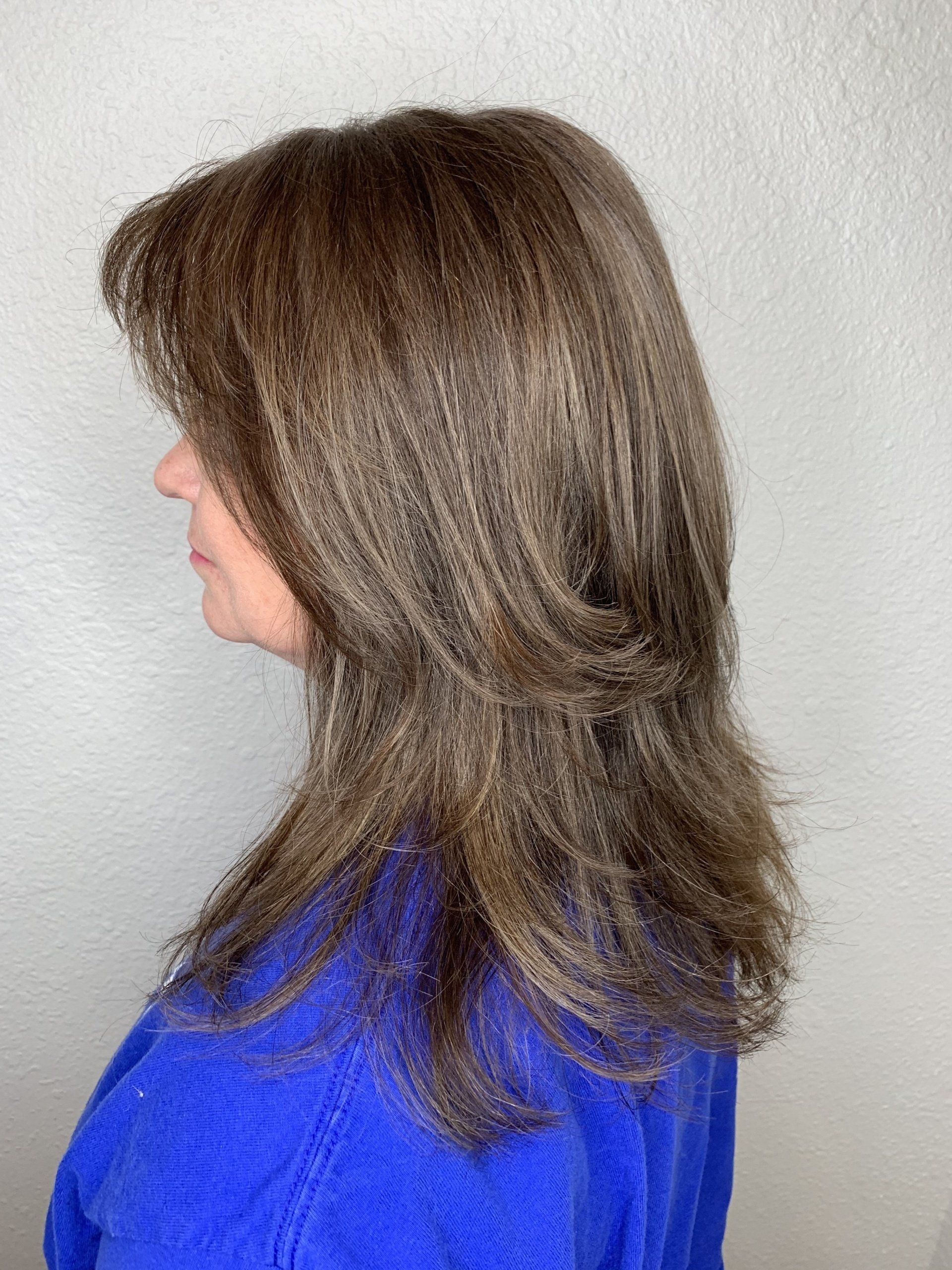 Side view of a person with long brown hair wearing a bright blue top