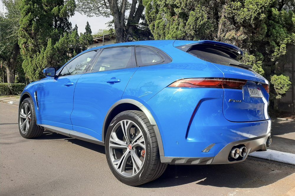 Um jaguar f pace azul está estacionado em um estacionamento.