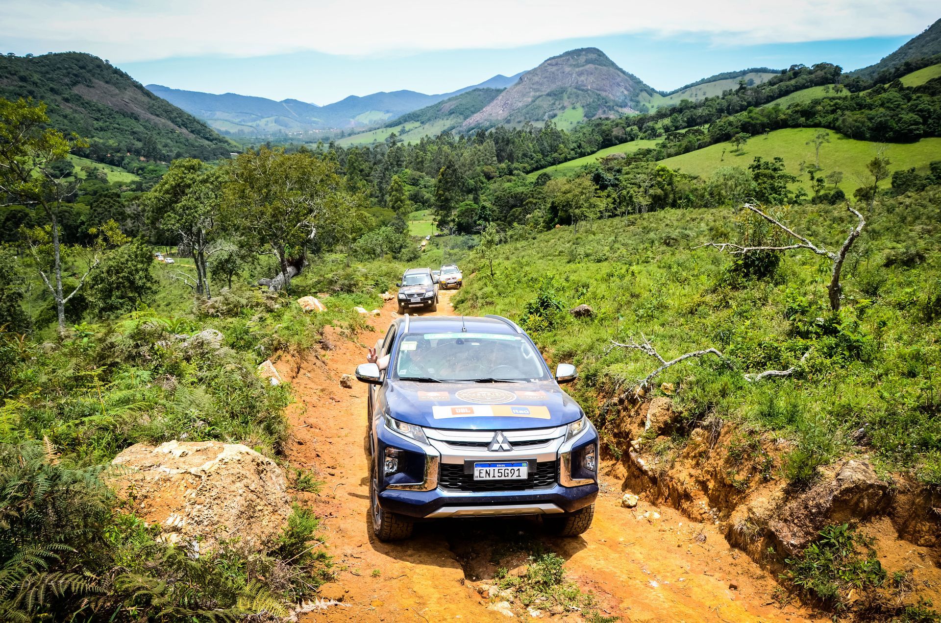 Um grupo de carros está dirigindo por uma estrada de terra.