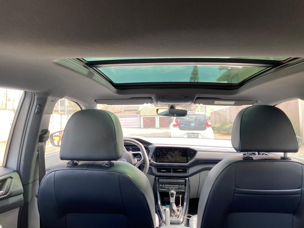 O interior de um carro com teto solar e bancos pretos.