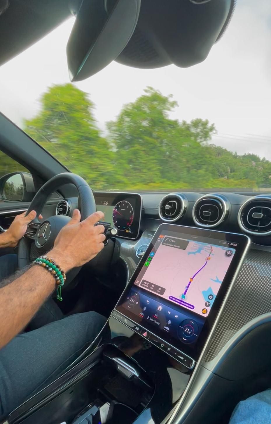 Um homem está dirigindo um carro com um tablet no painel.