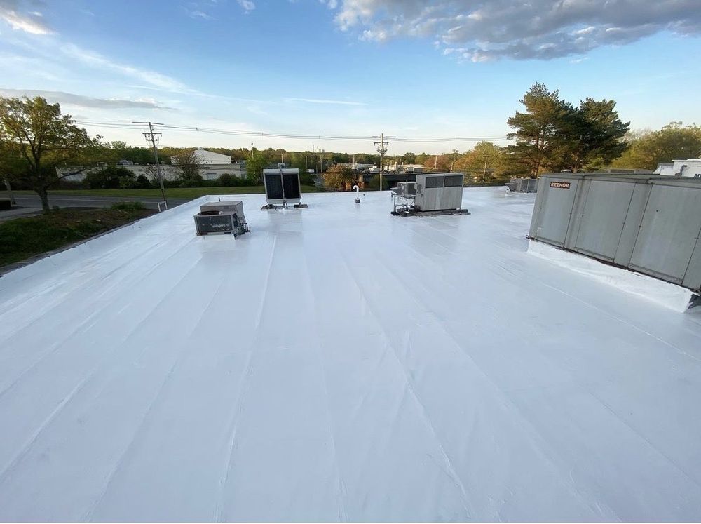 White commercial rooftop with HVAC units under a cloudy sky