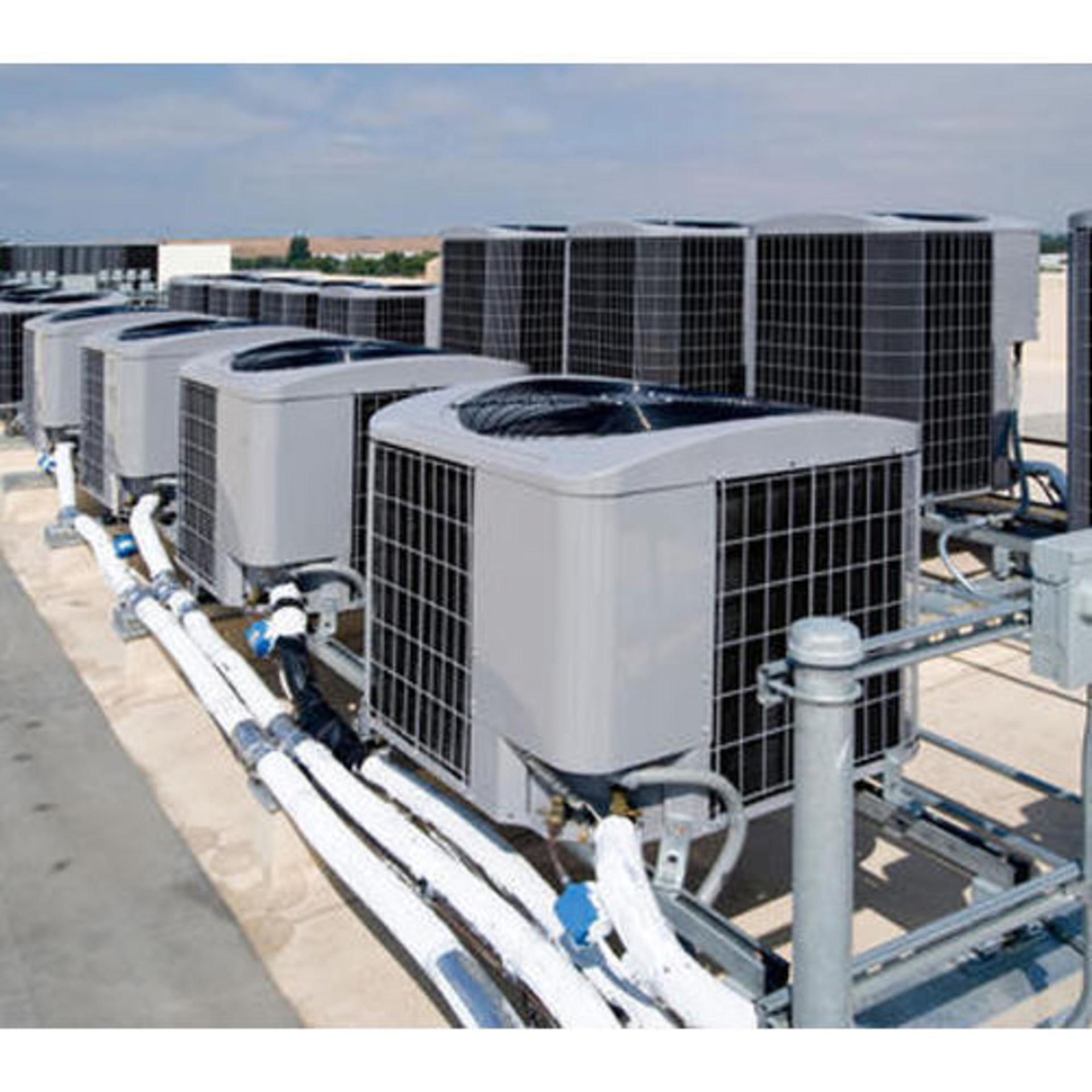 A row of air conditioners are sitting on top of a roof.