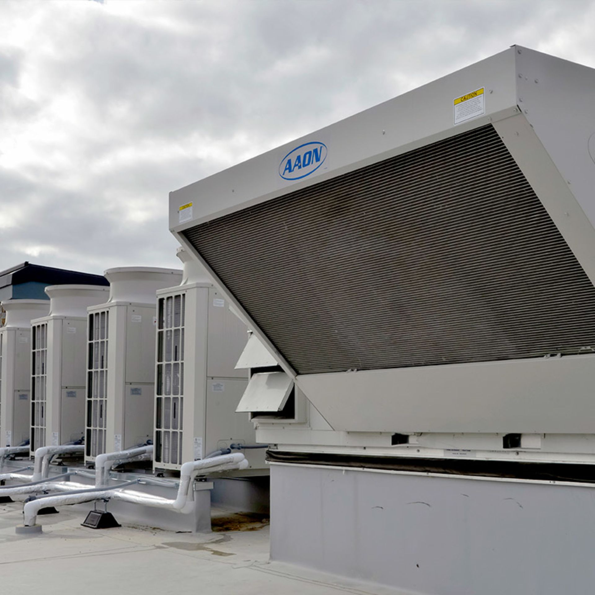 A row of air conditioners are sitting on top of a building.