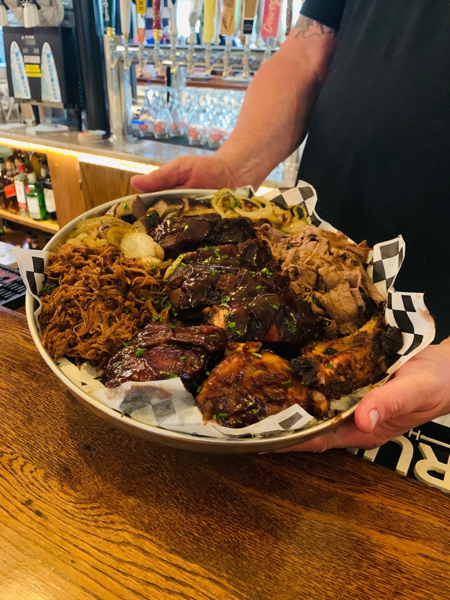Handheld plate piled with saucy barbecue meats and rice on a restaurant table