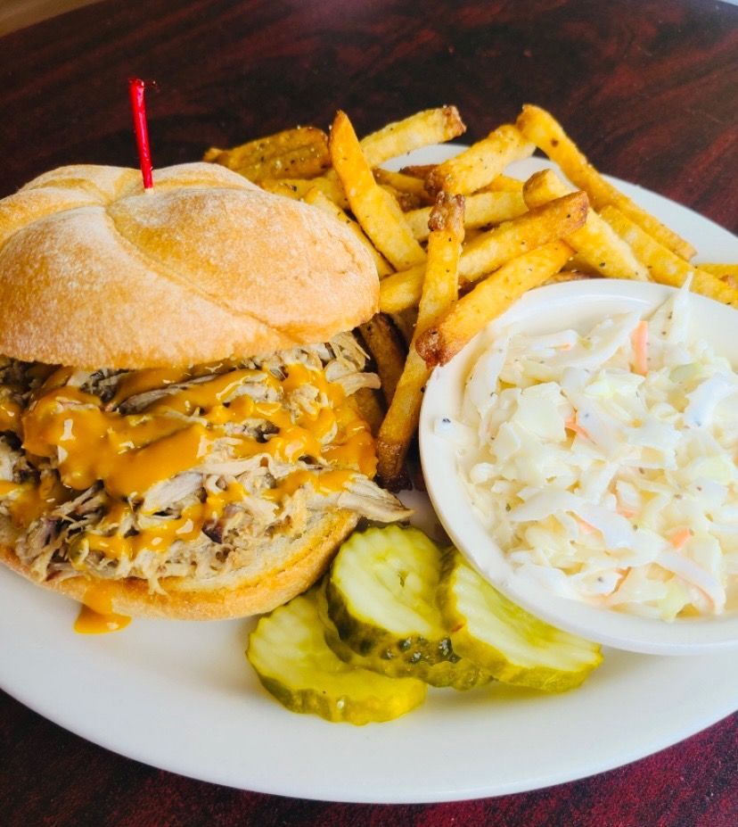 Cheeseburger with fries, coleslaw, and pickles on a white plate