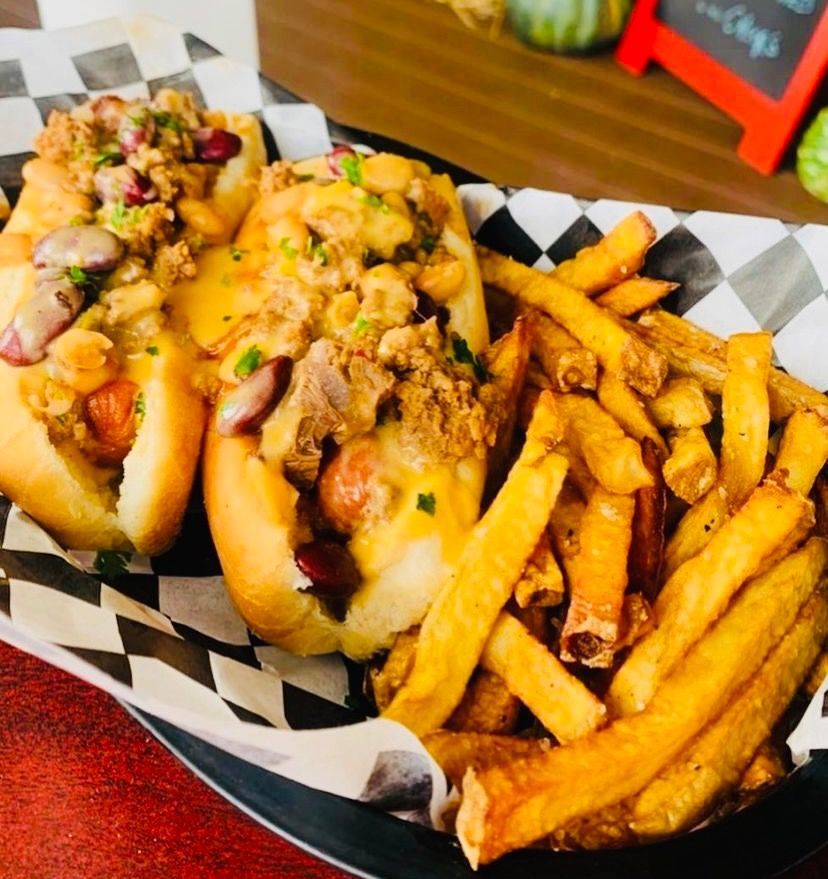 Two loaded hot dogs in a basket with seasoned French fries.