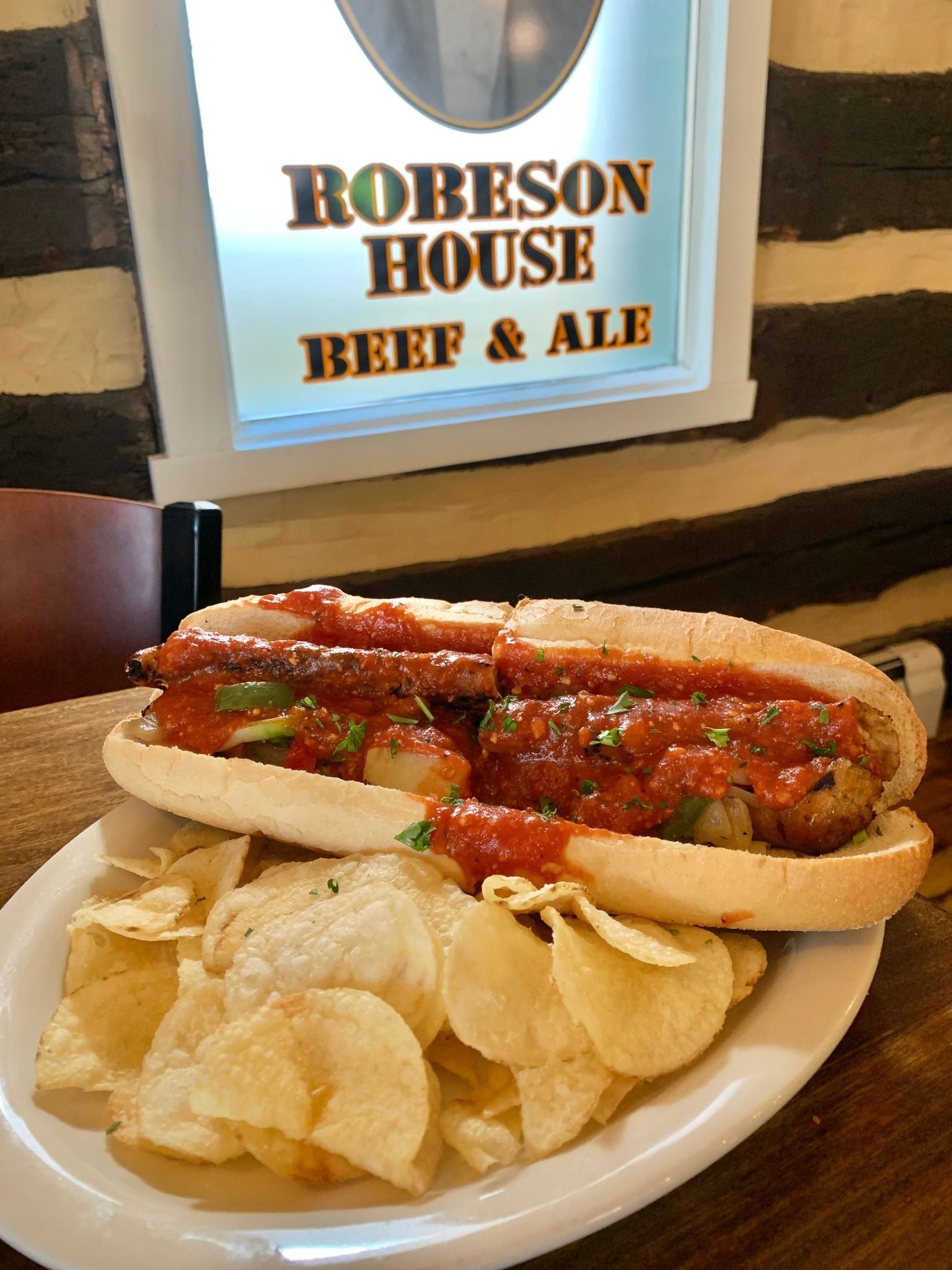 Hot beef sandwich on a white plate with potato chips at Robeson House Beef & Ale restaurant
