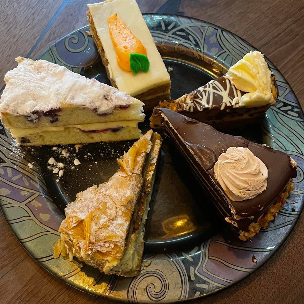 Assorted cake slices on a decorative plate, including chocolate, cream, and fruit-topped pieces