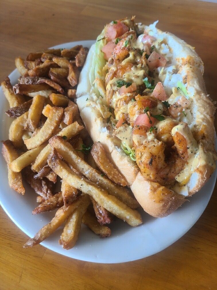 Sub sandwich topped with salsa beside seasoned fries on a white plate