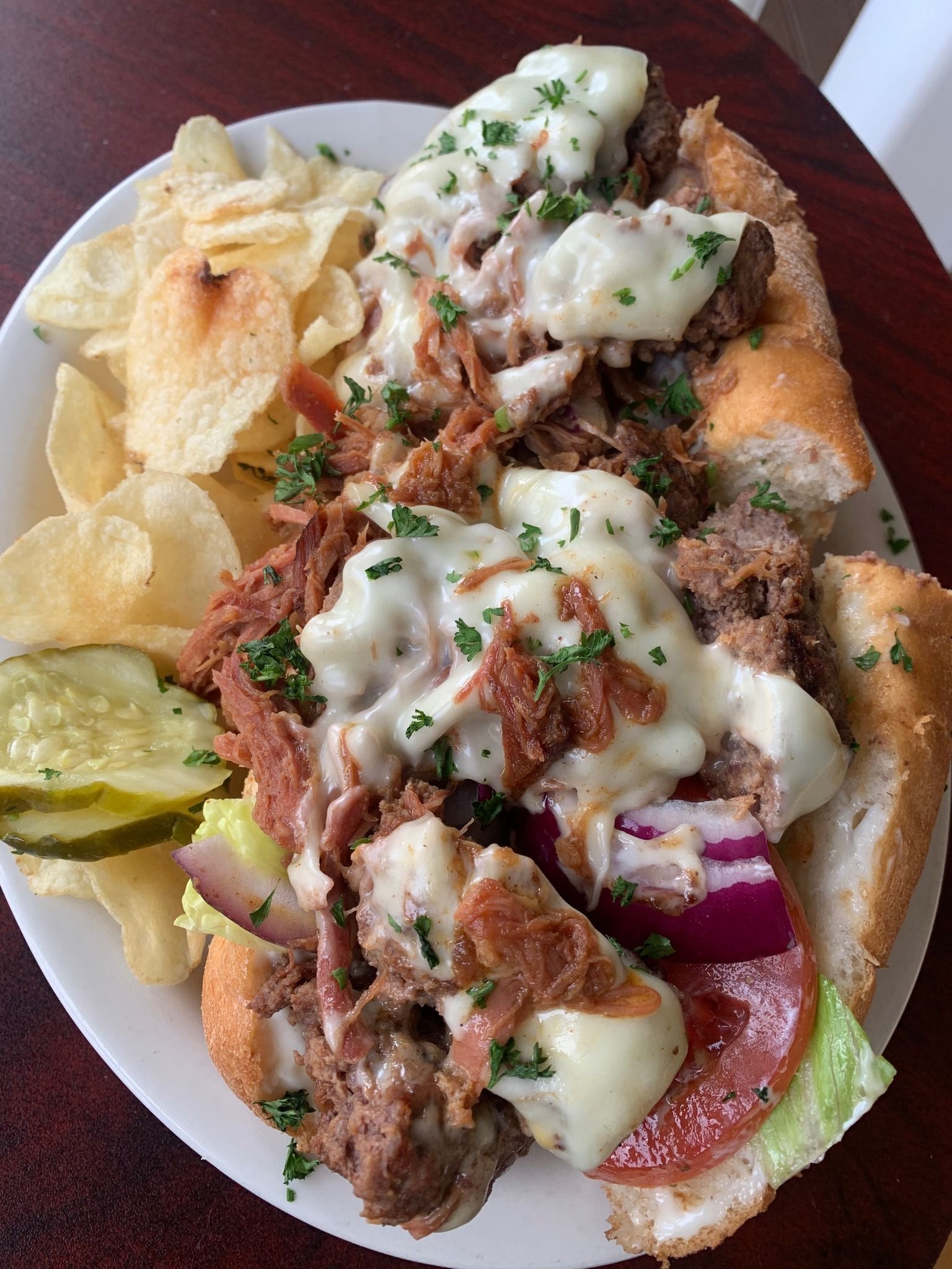 Taco salad plate with crispy shells, beef, lettuce, onions, chips, pickles, and white sauce
