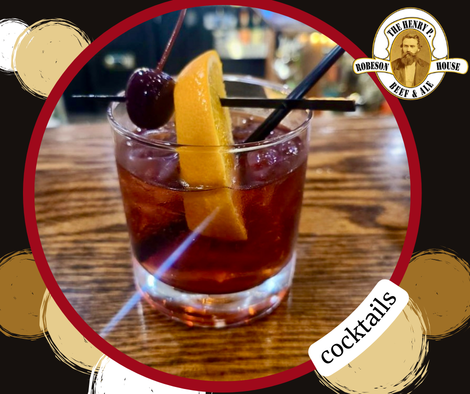 Cocktail in a lowball glass with orange peel and cherry on a wooden table