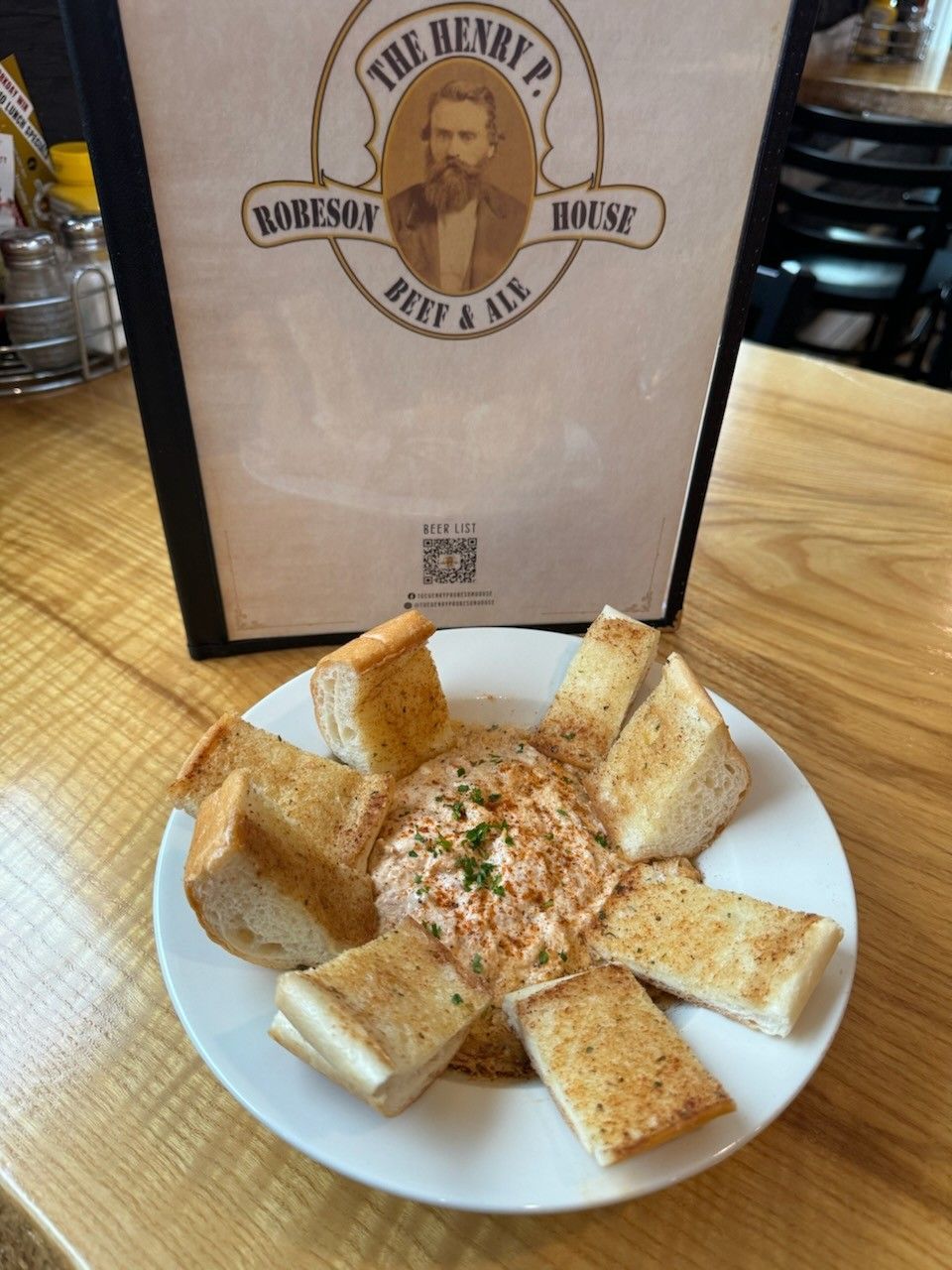 Basket of seasoned breadsticks on a white plate beside a restaurant menu.