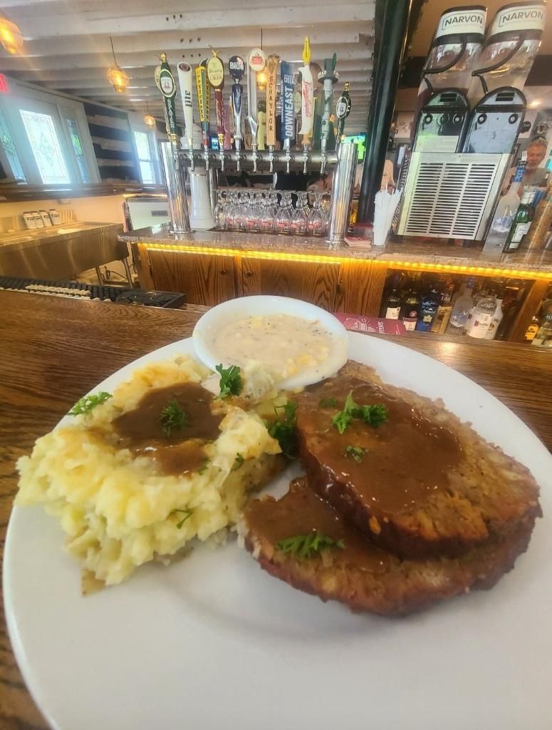 Plated steak and mashed potatoes at a bar, with beer taps and bottles in the background