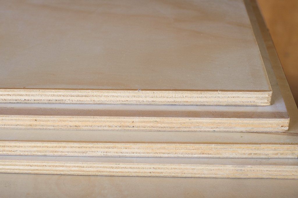 A stack of four rectangular wooden plywood panels with light-colored, smooth surfaces.
