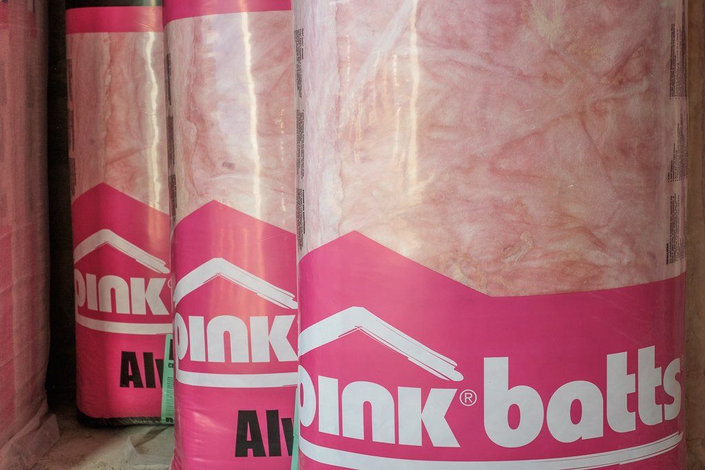 Close-up of several rolls of pink fiberglass insulation, with branded