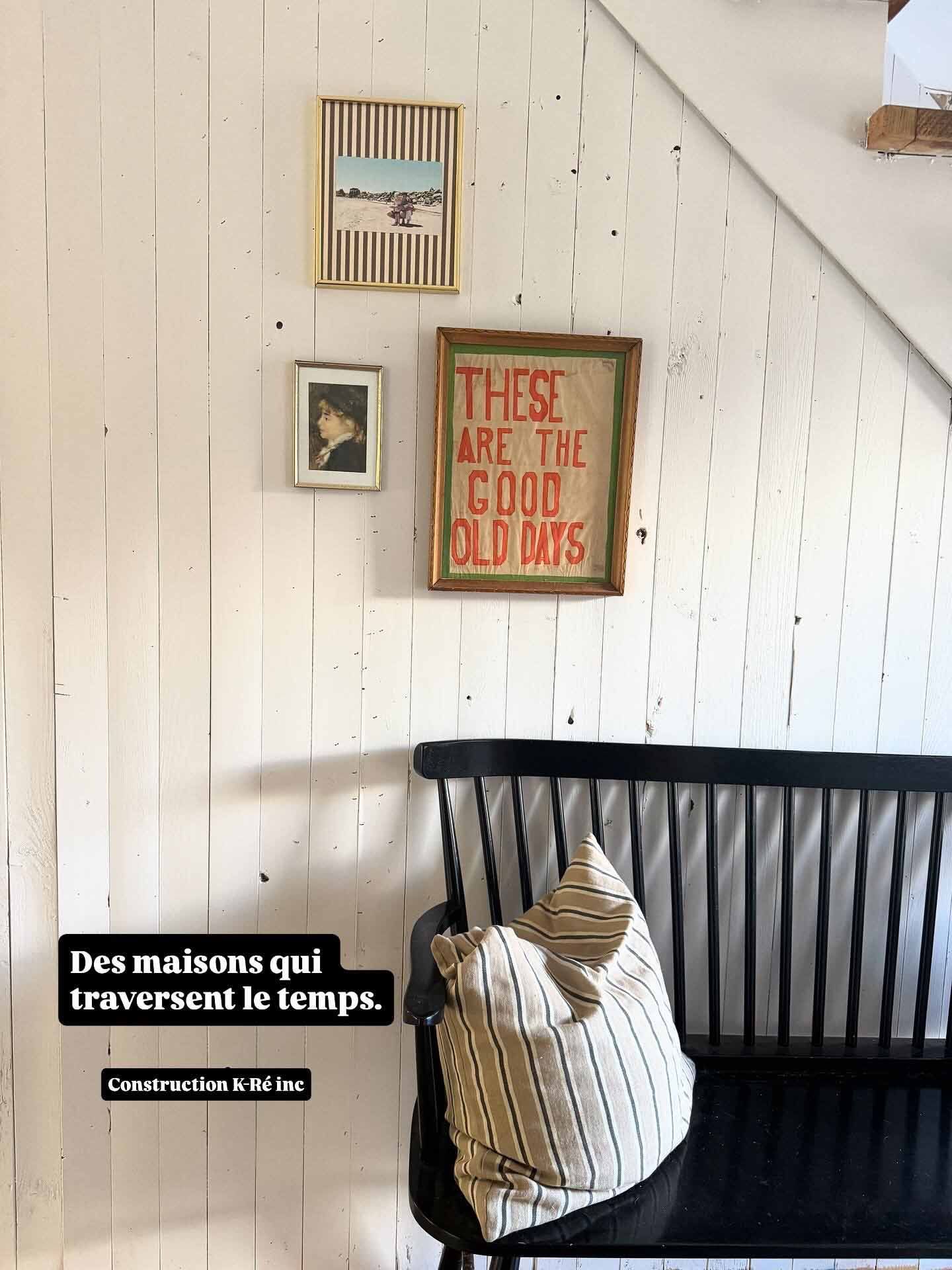 Banc noir avec coussin sous un tableau encadré sur un mur blanc.