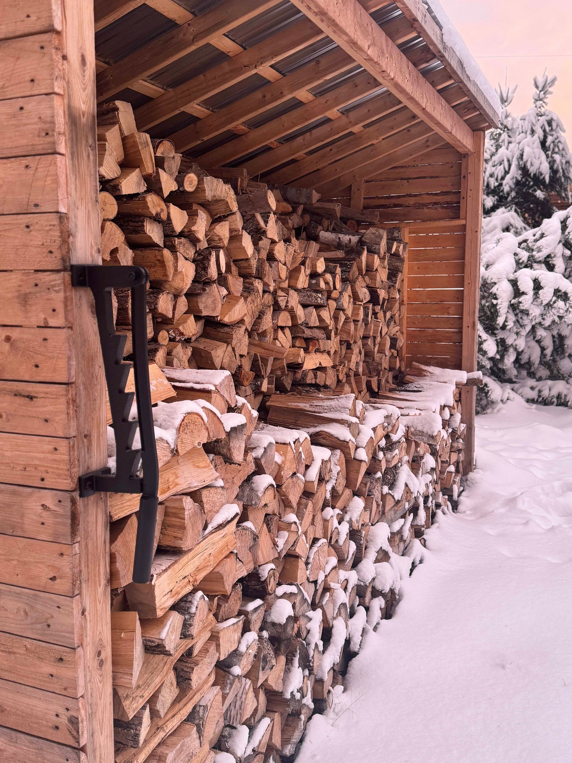 Abri à bois rempli de bois de chauffage empilé et recouvert de neige. Structure en bois en hiver.