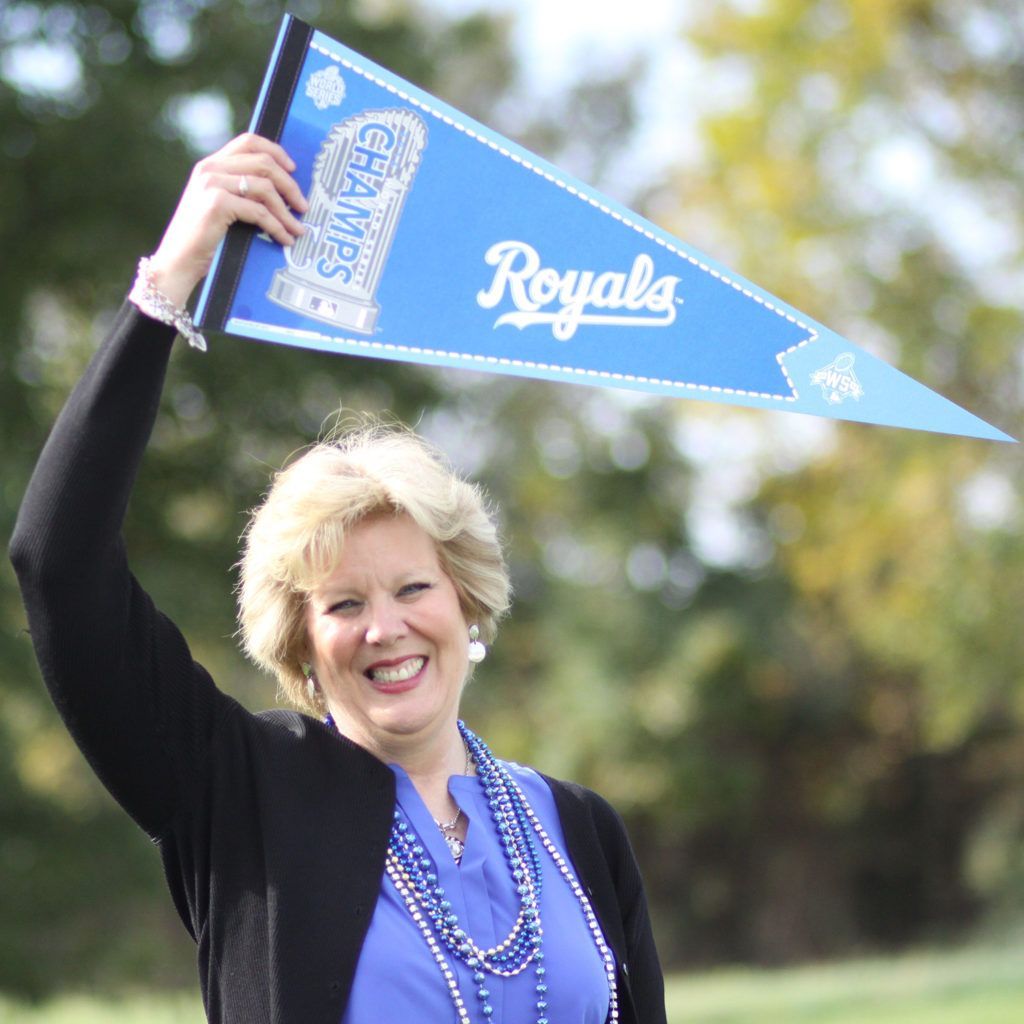 Kari Simpson A Kari Simpson is holding up a blue royals pennant
