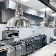 Une cuisine avec des appareils électroménagers en acier inoxydable et des lampes suspendues au plafond