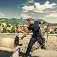 Un homme se tient debout sur un toit et tient un tuyau.