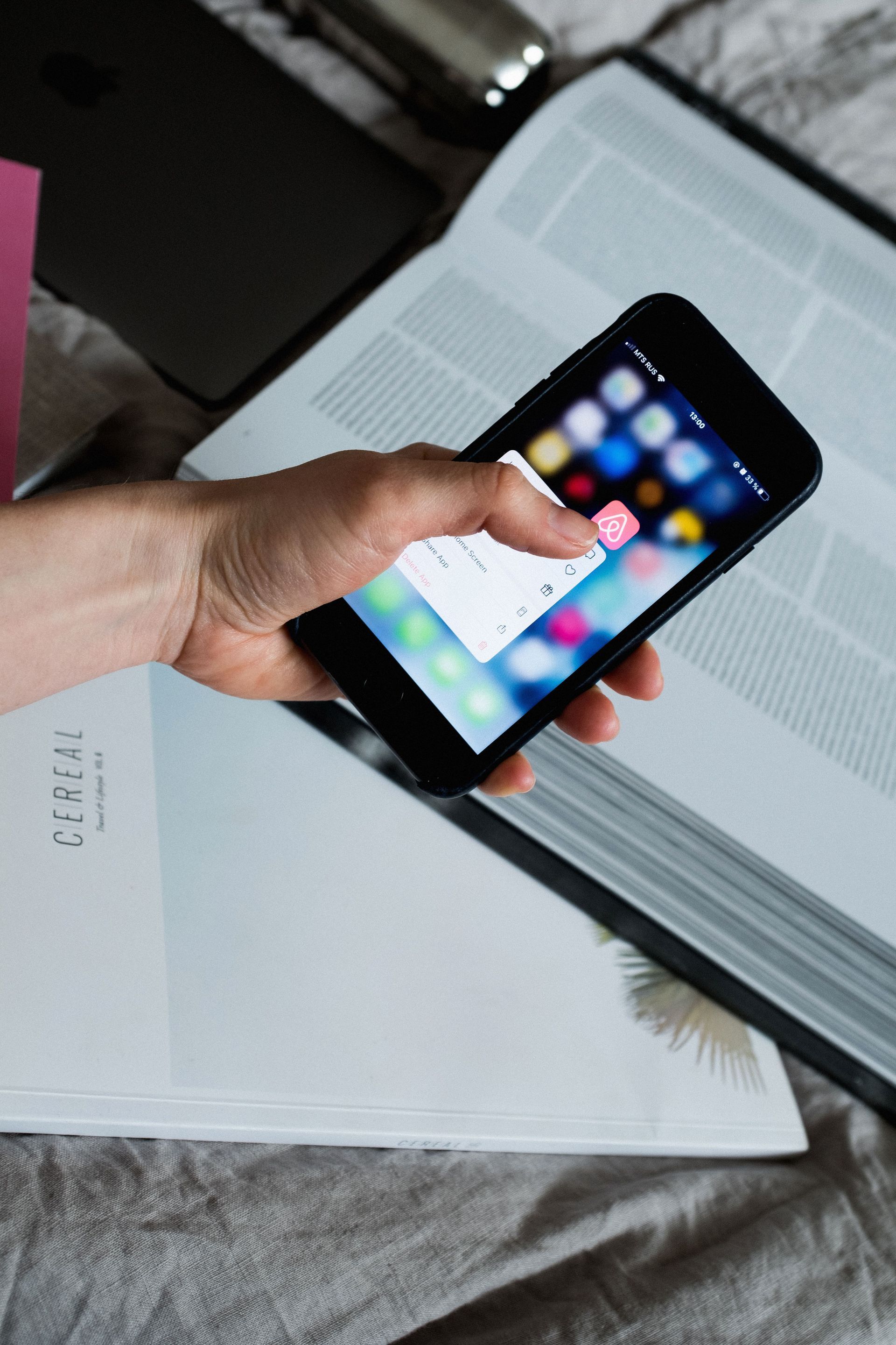 Hand holding a smartphone above a notebook next to a laptop – book directly with CoyHomes