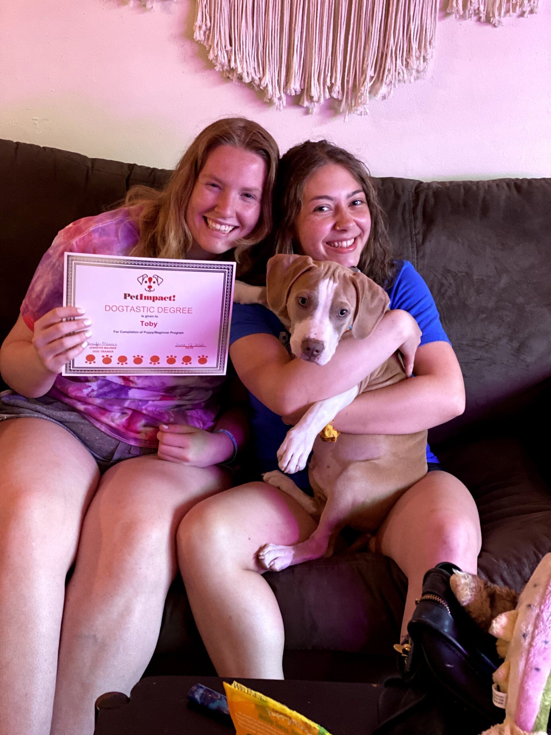 Dog Toby With Its Owners Holding Certificate — St. Louis, MO — PetImpact!