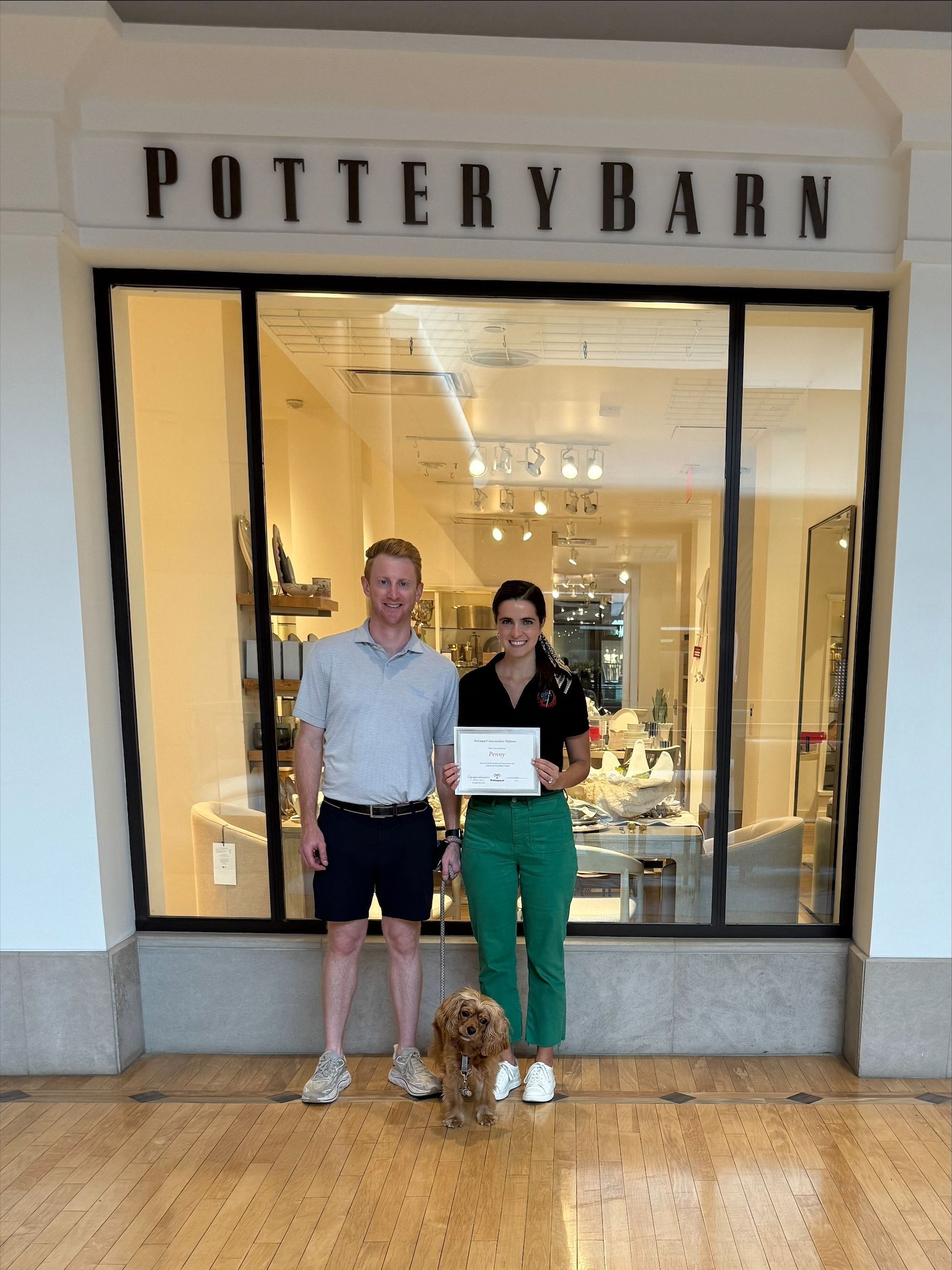 A couple holding a certificate with their dog.