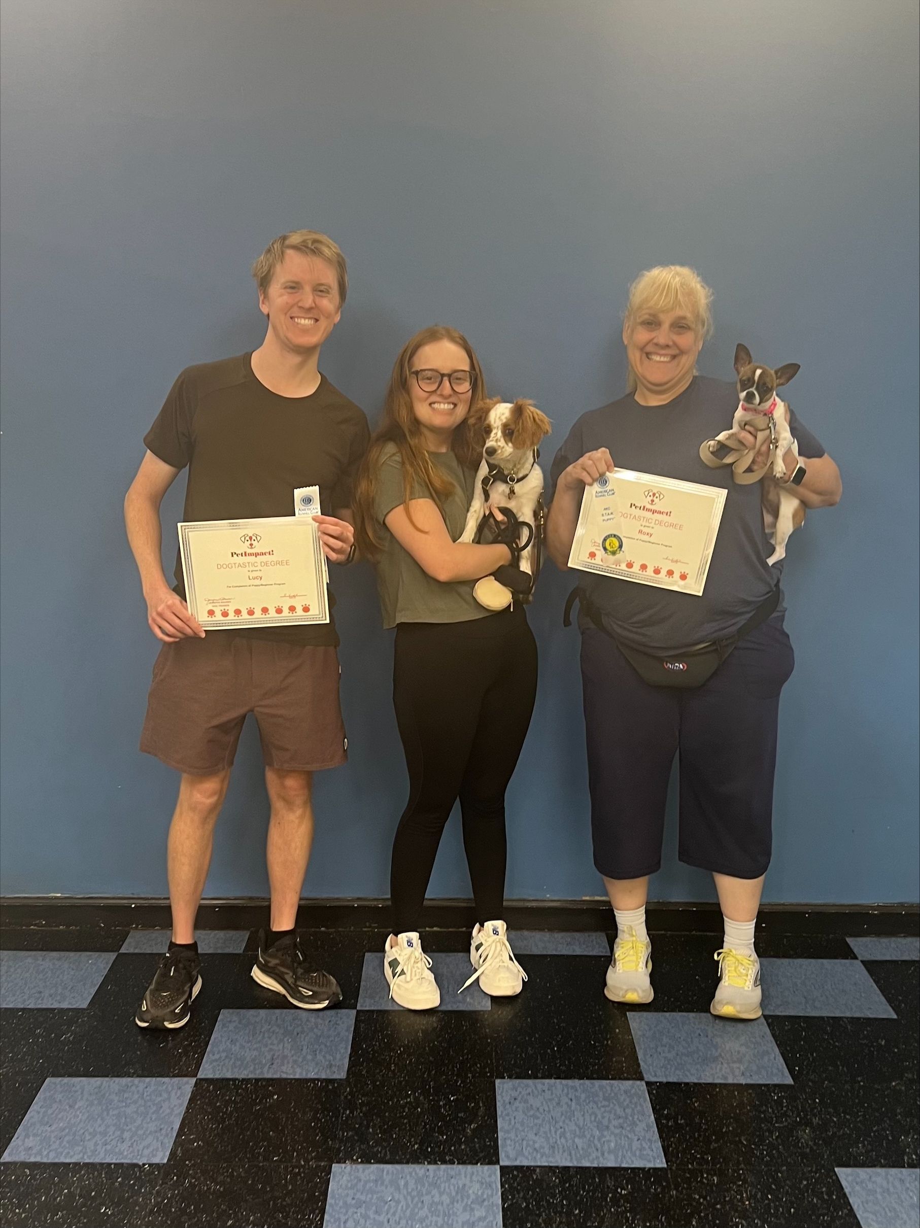 A group of people standing next to each other holding puppies and certificates.