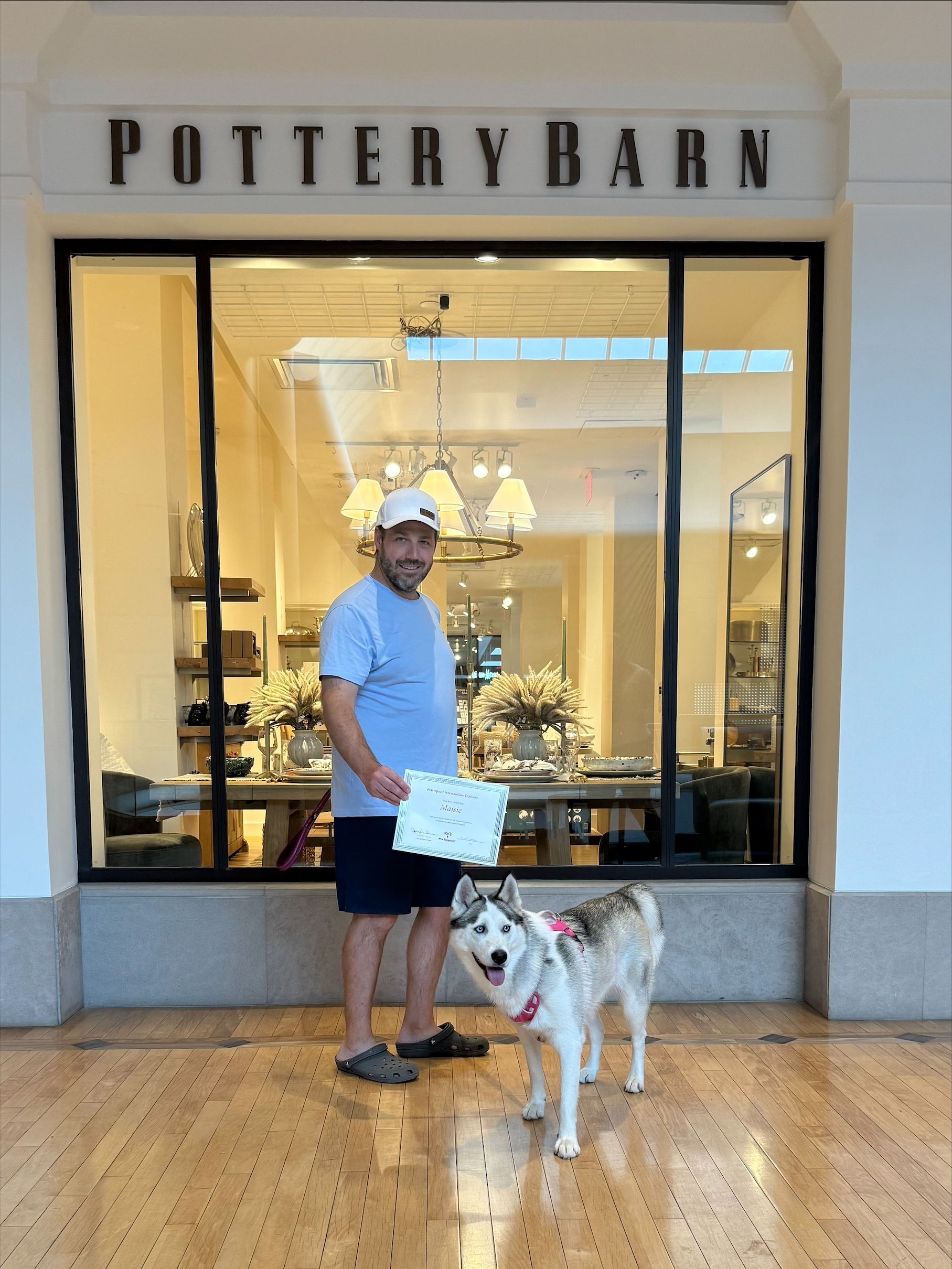 Man standing with a dog outside a Pottery Barn store entrance