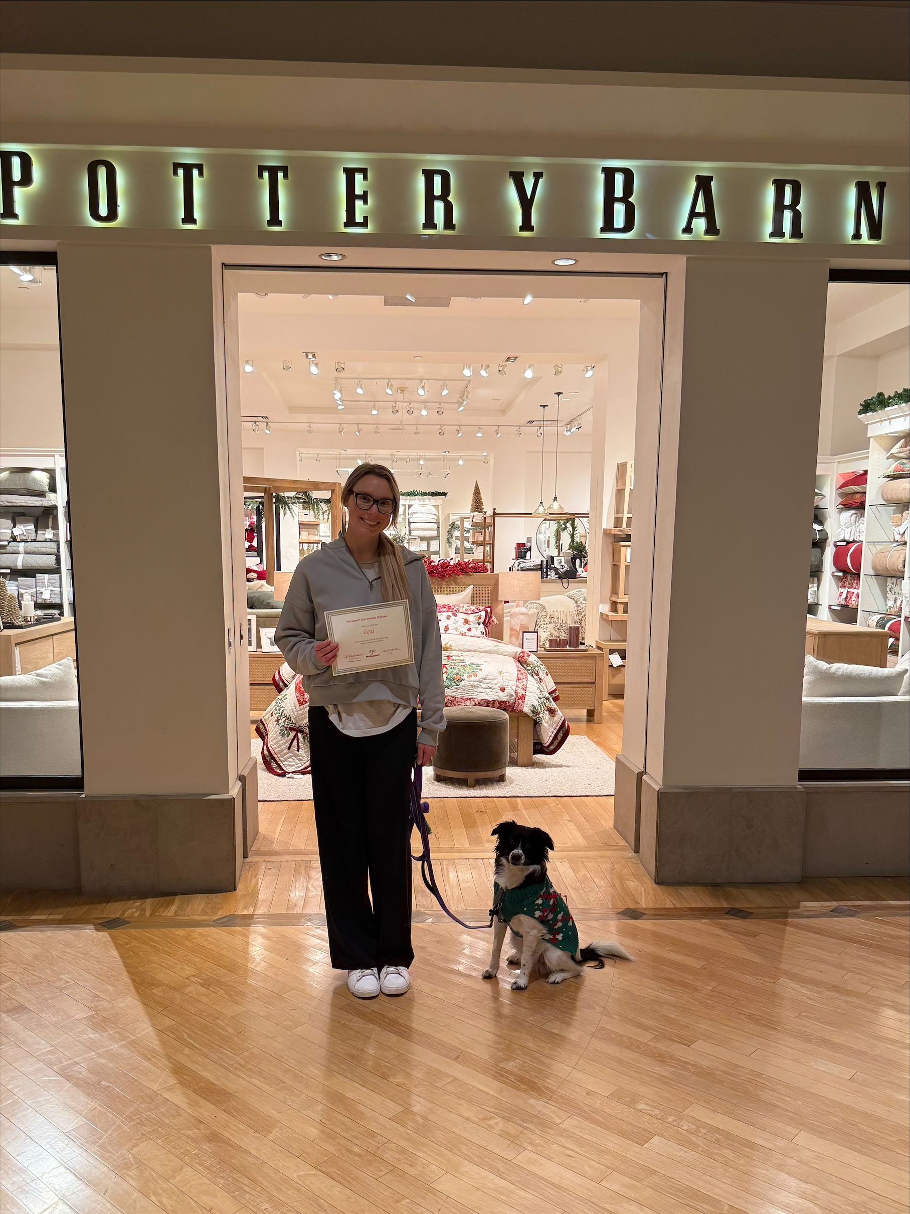 Person standing with a dog at the entrance of a Pottery Barn store.
