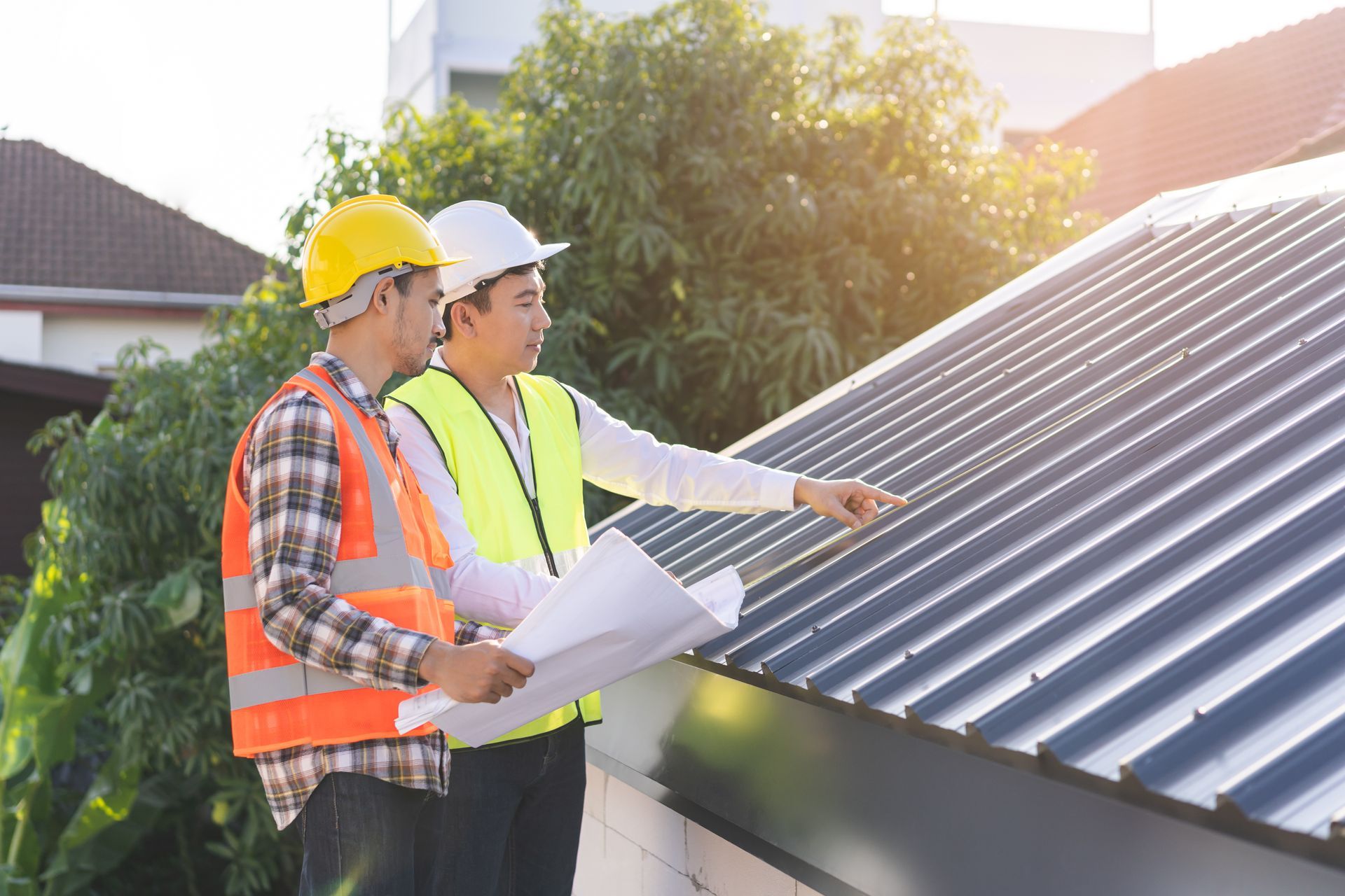 Two workers in hard hats inspecting a solar panel roof with plans in hand