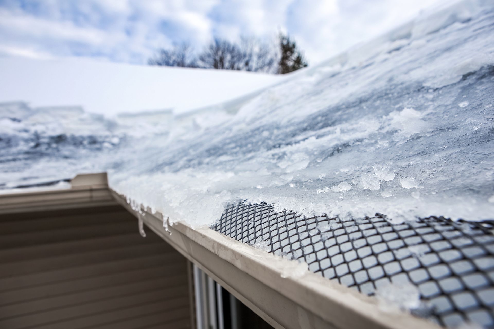 Snow-covered roof edge with icy eaves and a roof heat cable beneath the snow