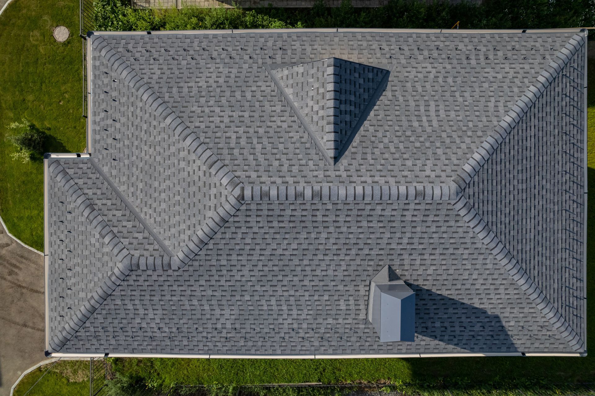 Aerial view of a gray shingle-roofed house with two dormers and a small front porch.